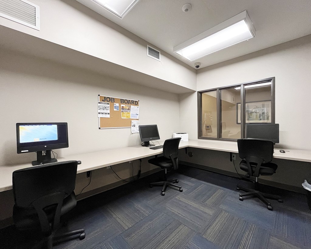 A room with a JOB BOARD on the wall and two computers on desks.
