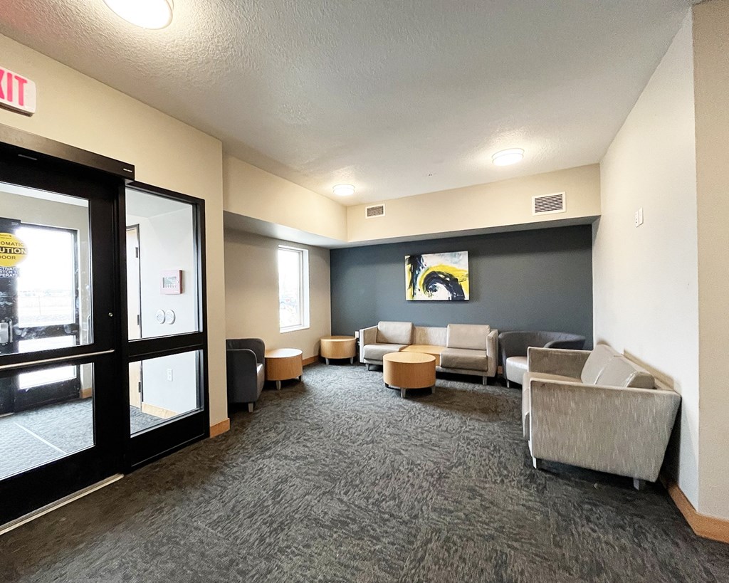 A waiting room with grey carpeting and a large window.