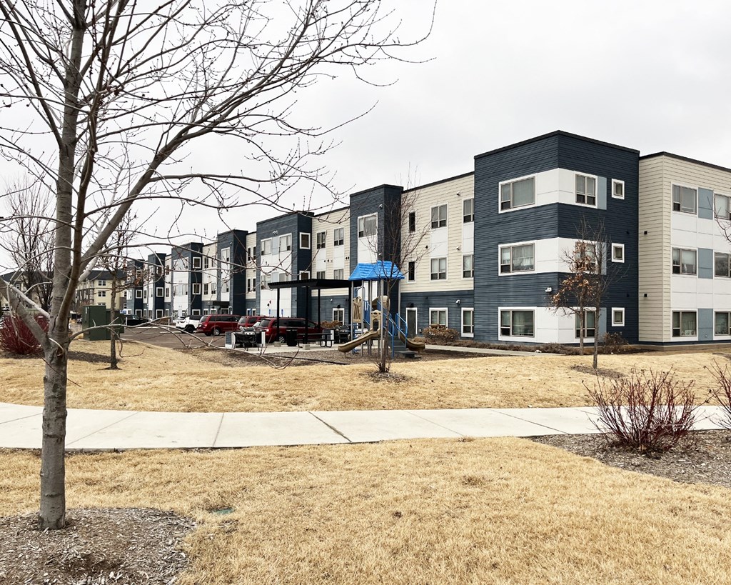 A row of modern apartment buildings with a tree in the foreground.