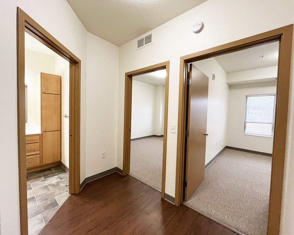 A room with a wooden floor and a grey carpet.