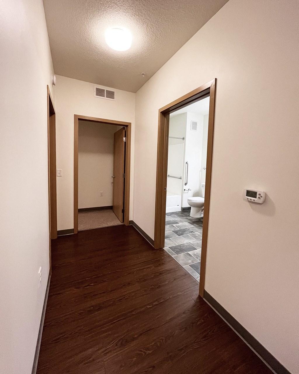 A hallway with wood floors and white walls.