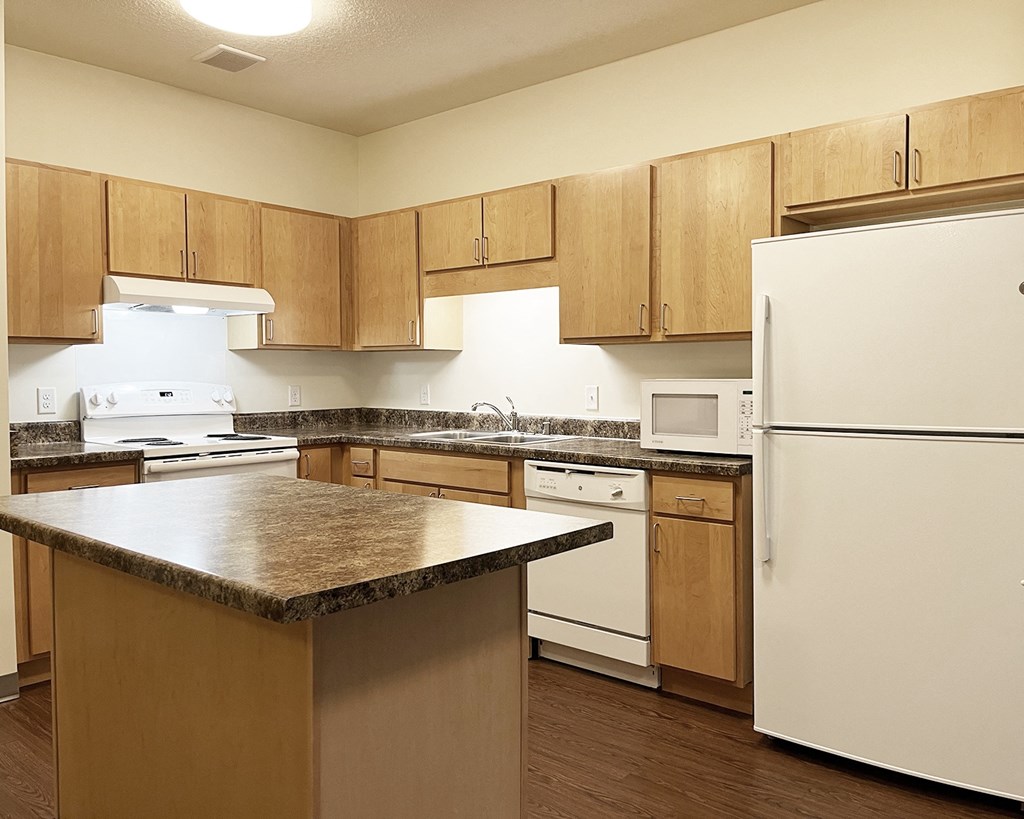 A kitchen with white appliances and wooden cabinets.