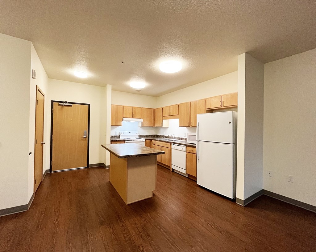 A kitchen with white appliances and wooden cabinets.