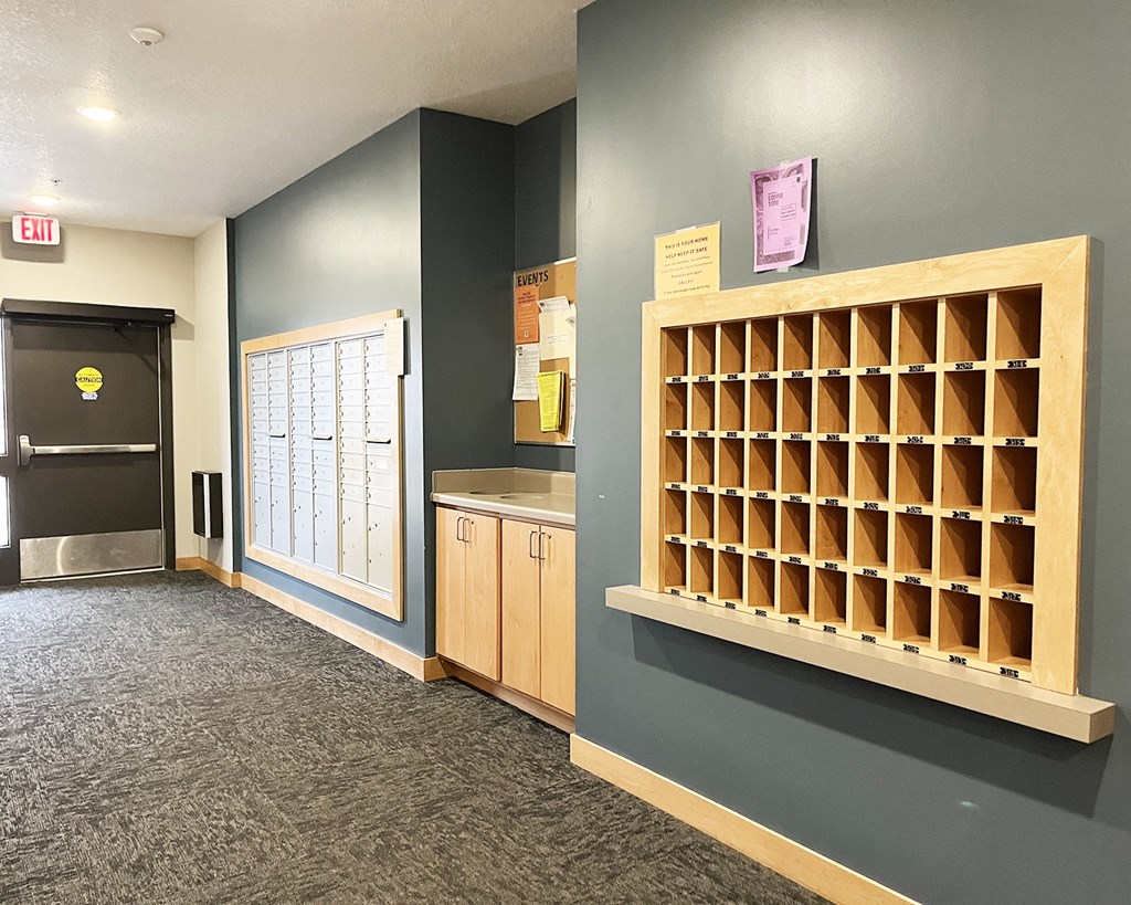 A long hallway with a bulletin board on the wall.
