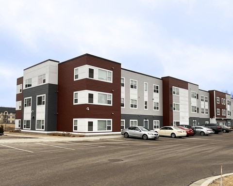 A parking lot in front of a multi-story apartment building.