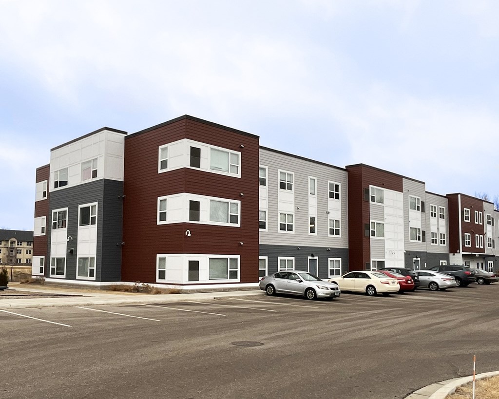 A parking lot in front of a multi-story apartment building.