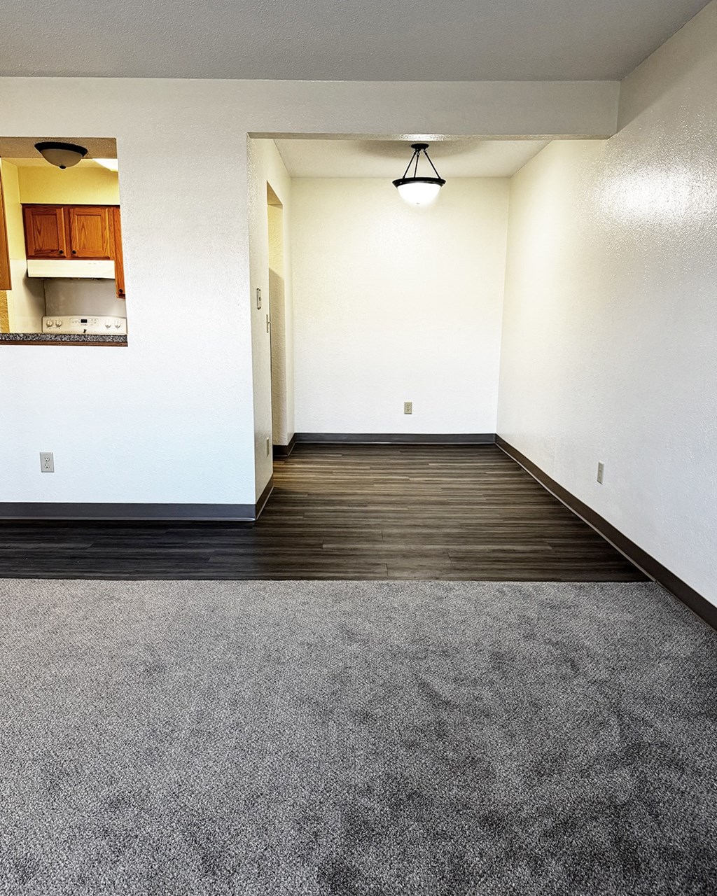 A room with a grey carpet and wooden floor.