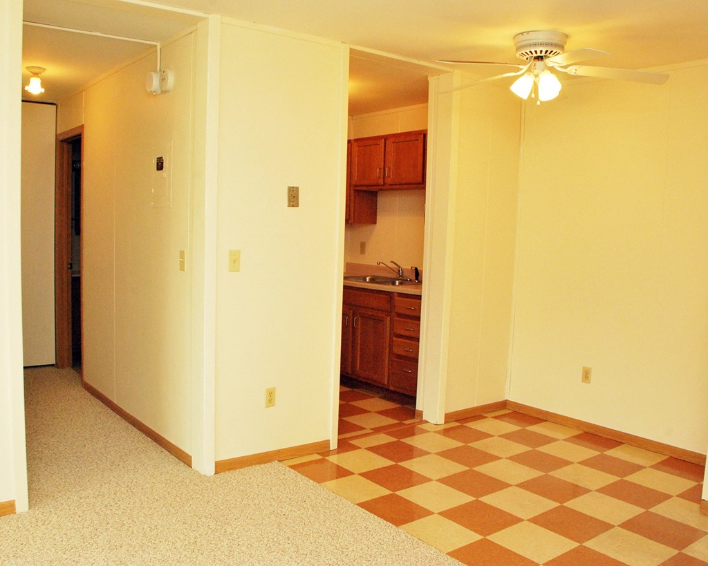 an empty living room with a checkered floor and a kitchen