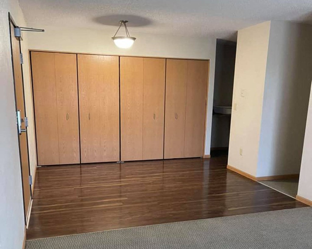 an empty living room with wood floors and cabinets