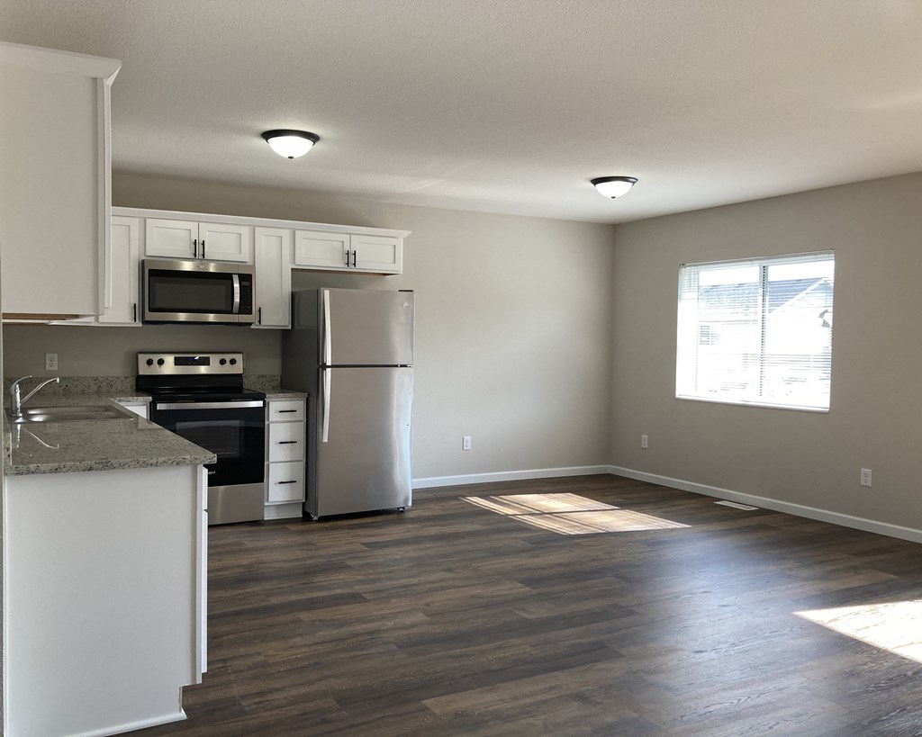 an empty kitchen and living room with hardwood floors and a window
