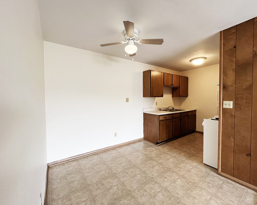 an empty kitchen and living room with a ceiling fan