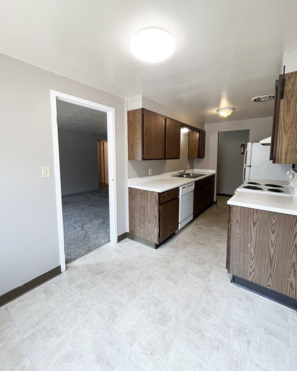 an empty kitchen with wood cabinets and a white counter top