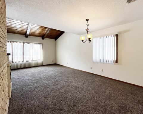A room with a carpeted floor and a chandelier hanging from the ceiling.