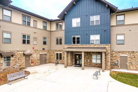 A courtyard with a bench and a building with a blue section in the middle.