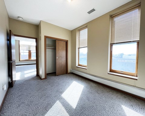 an empty living room with three windows and a door