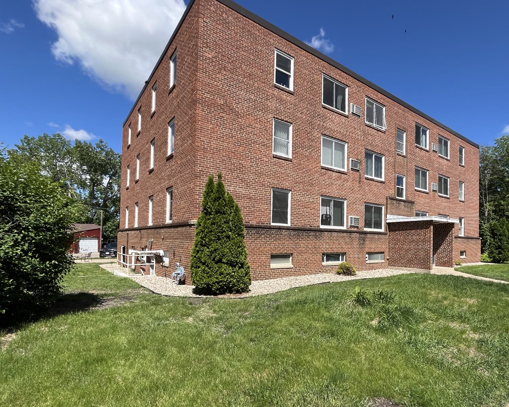 a brick building on a hill with grass and trees