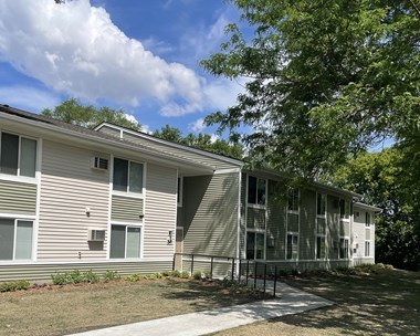 a picture of the exterior of a gray apartment building with a blue sky in the background
