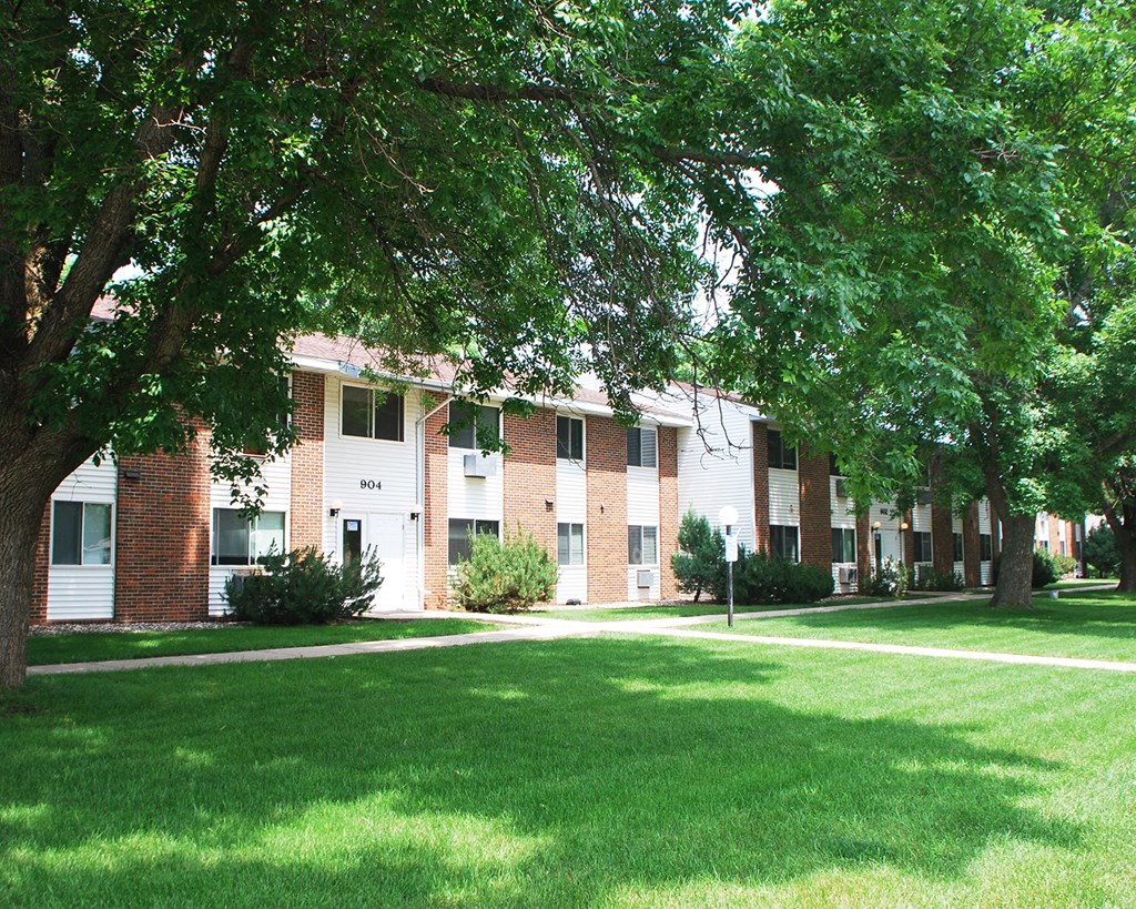 a large brick apartment building with green grass and trees