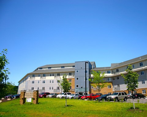 A parking lot in front of a multi-story apartment building.