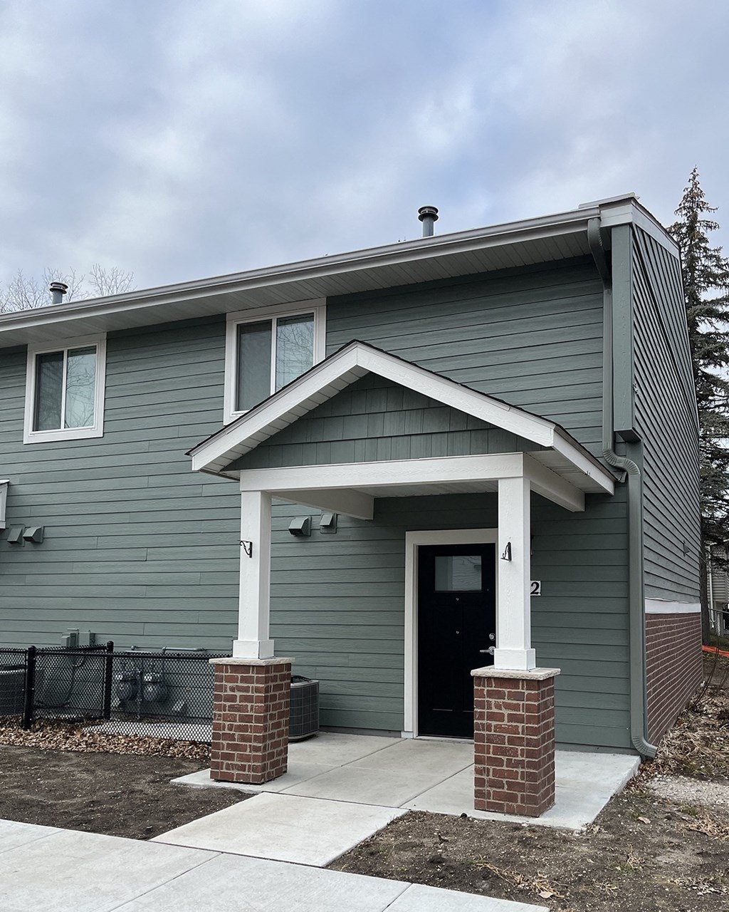 a gray house with white pillars and a front door