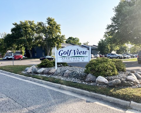 a sign for golf view apartments in front of a parking lot