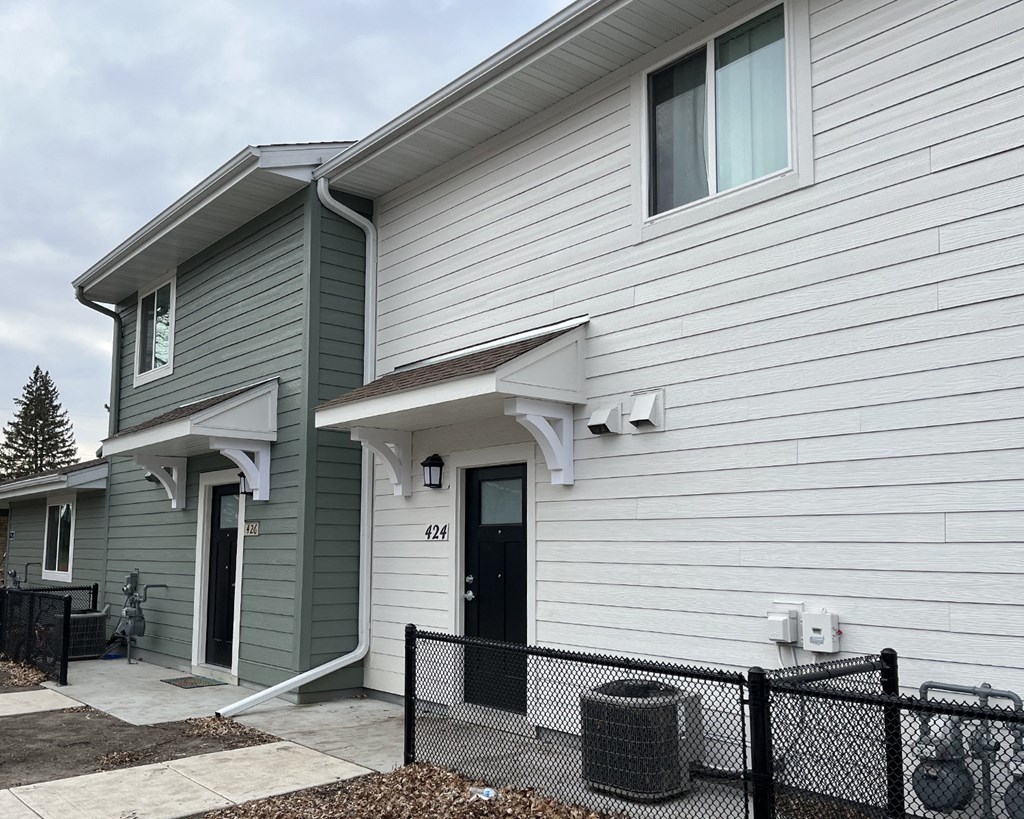 a white house with green siding and a black door