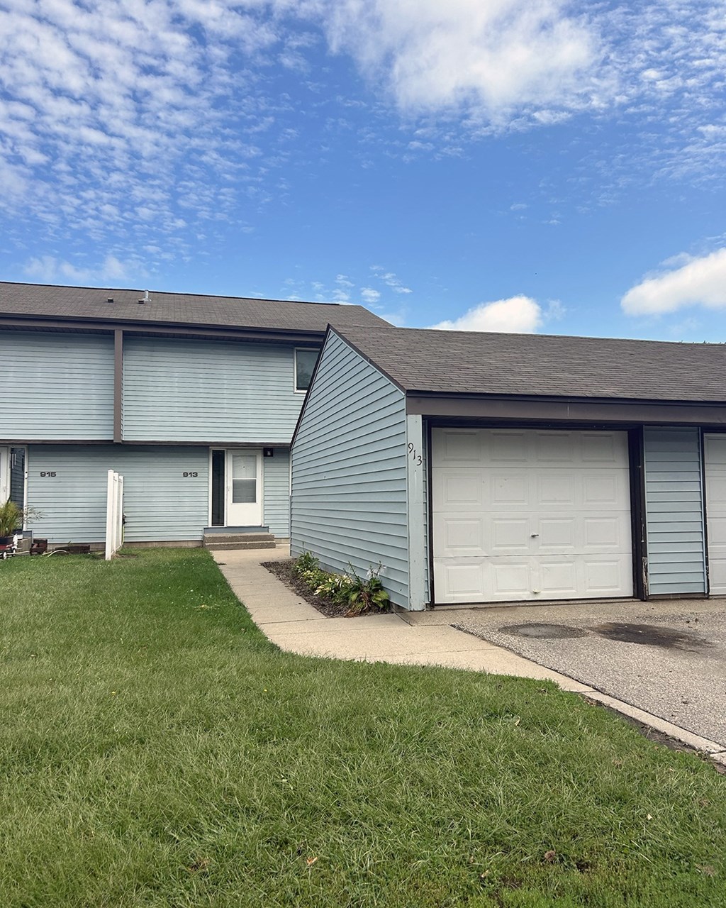 A blue house with a white door and a garage door.