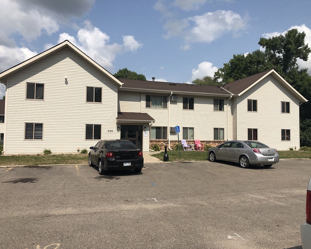 a large white building with two cars parked in front of it