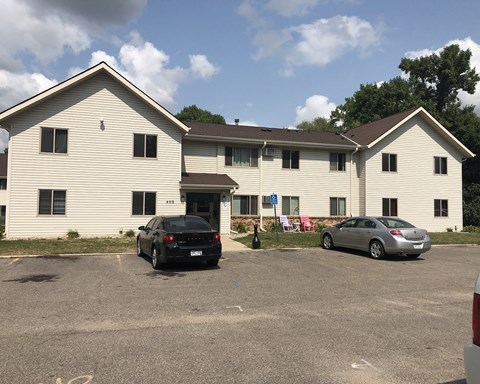 a large white building with two cars parked in front of it