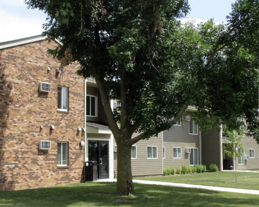 an apartment building with a tree in the yard