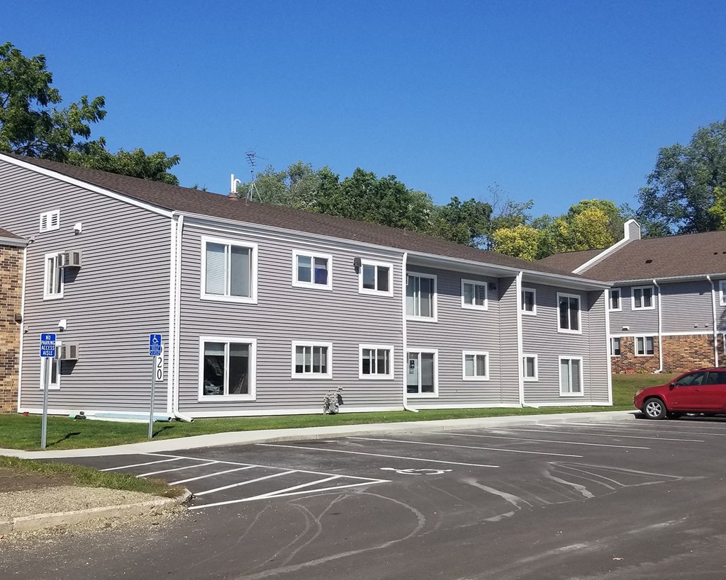 a building with a parking lot and a red car in front of it