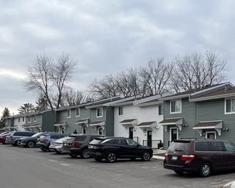 a row of apartment buildings with cars parked in front