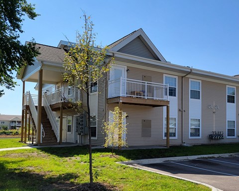 a tan house with stairs and a tree in front of it