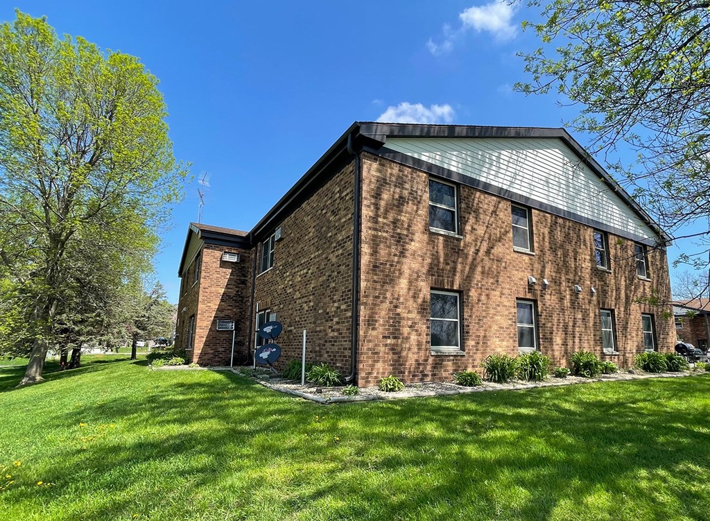 a brick house with a green lawn and a blue sky