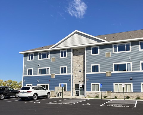 A blue building with a parking lot in front.