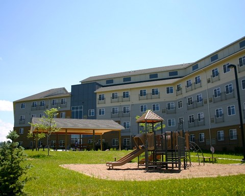 a playground in a park in front of an apartment building