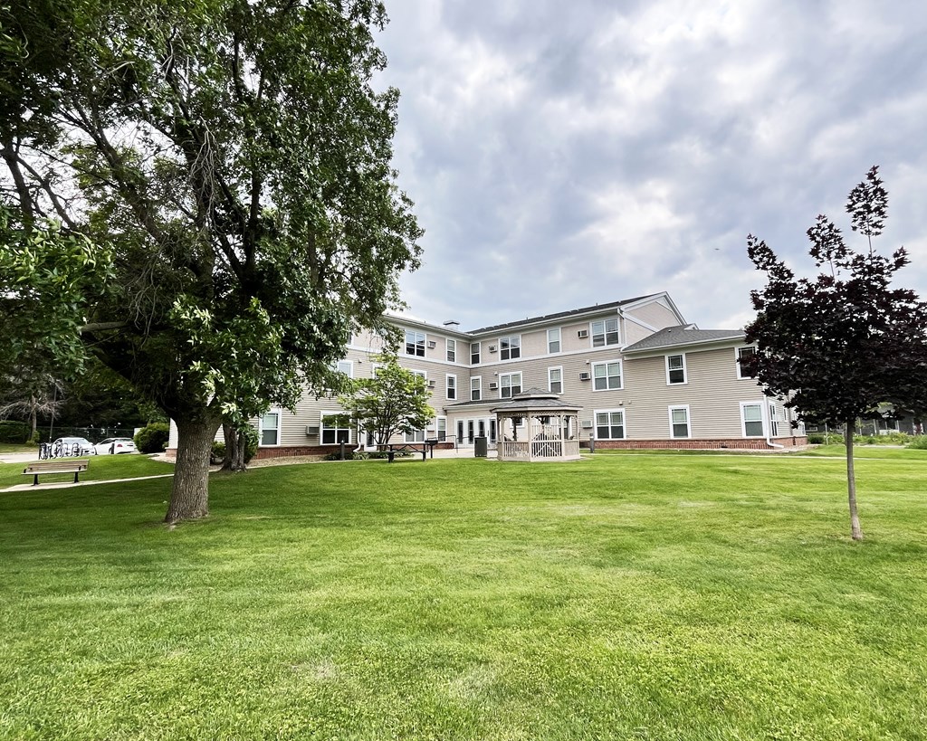 A large grassy area in front of a building with trees on the sides.