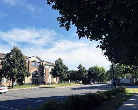 A parking lot in front of a building with trees and a clear sky.