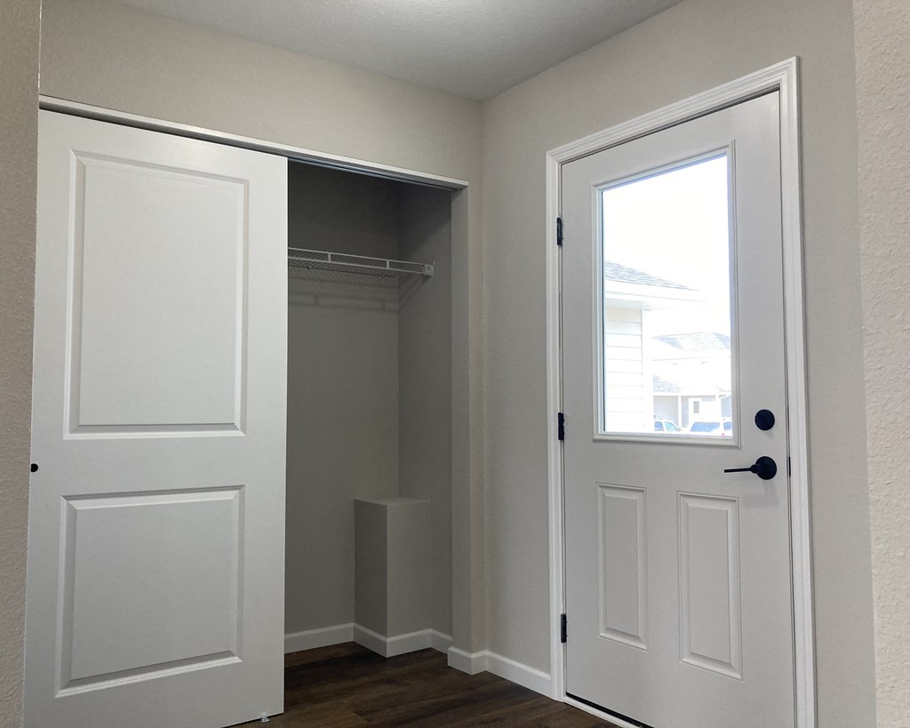 a walk in closet in a bedroom with two doors and a window