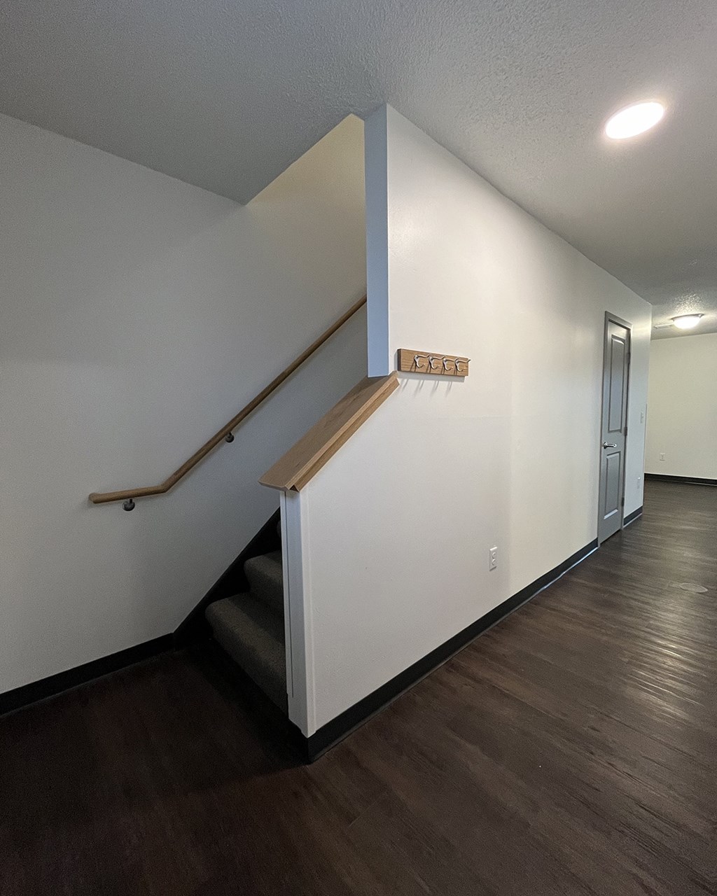a stairwell in a living room with white walls and a railing and a door