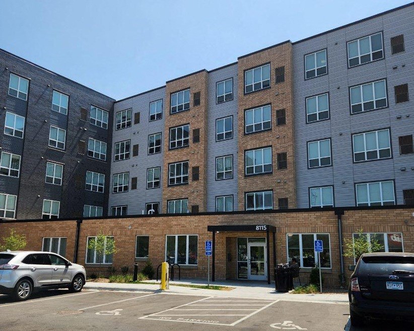 a brick apartment building with cars parked in front of it