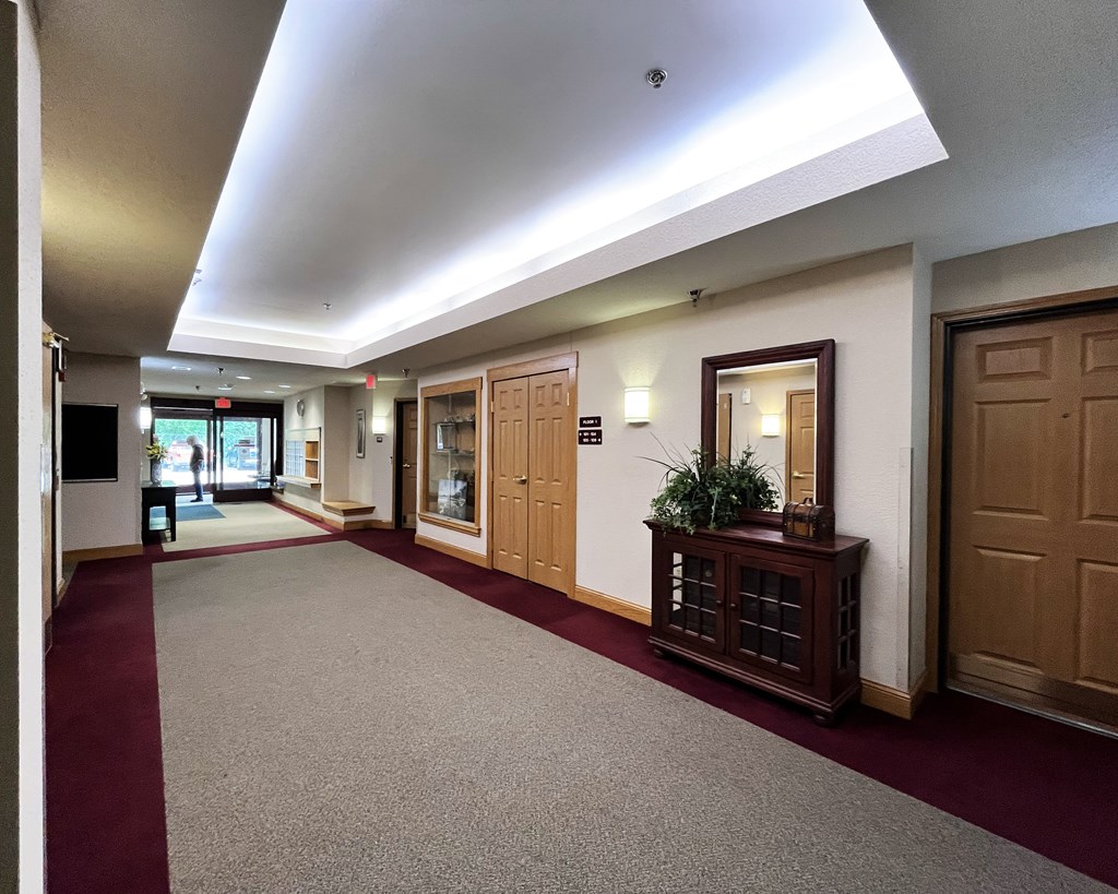 A hallway with a red carpet and wooden doors.