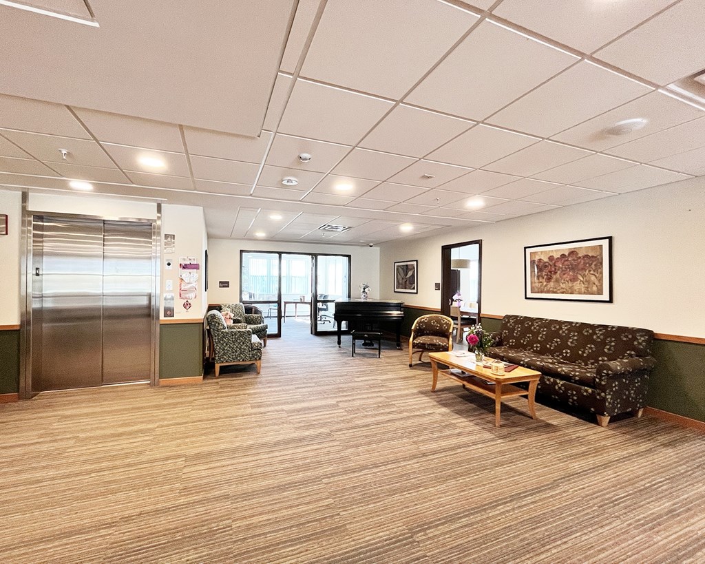 A spacious waiting room with a piano, chairs, and a couch.