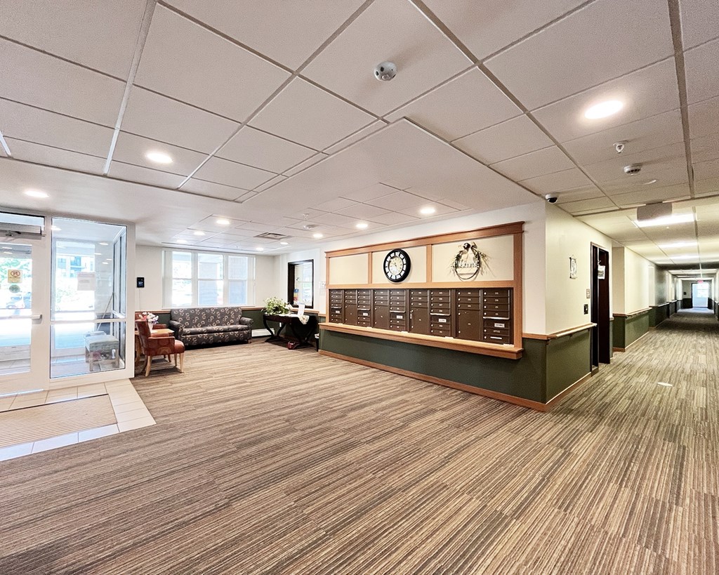 A long hallway with a couch and a clock on the wall.