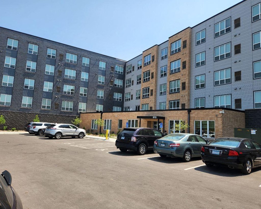 a parking lot with cars in front of an apartment building
