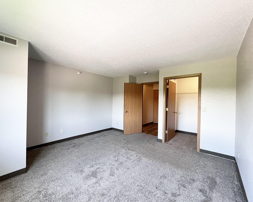 A room with carpeted floor and two wooden doors.