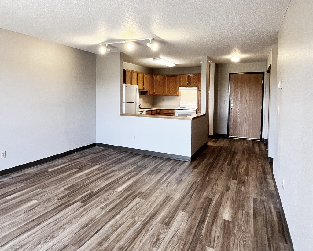 A kitchen with wooden floors and a view into the adjoining room.