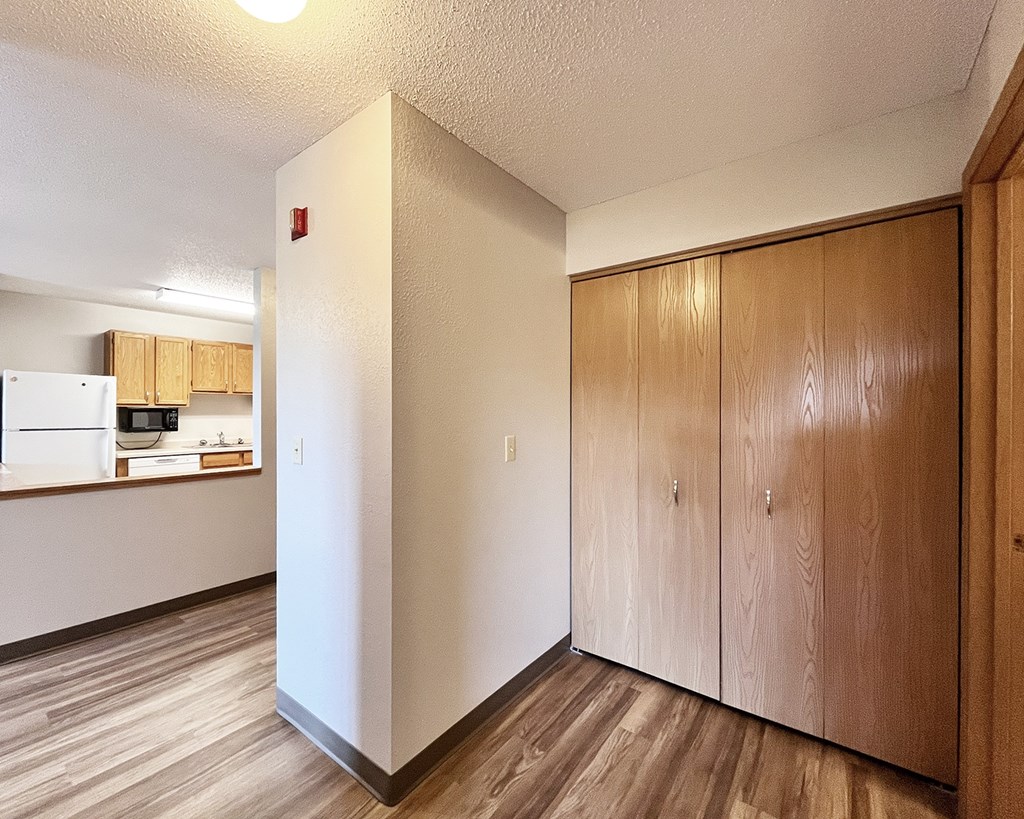 A kitchen area with wooden floors and cabinets.