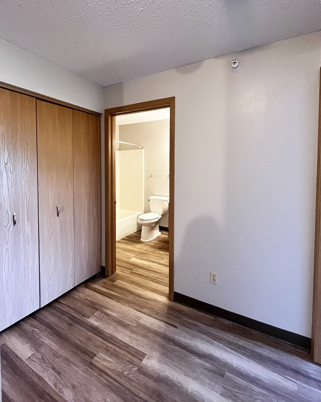 A bathroom with a toilet and a wooden cabinet.
