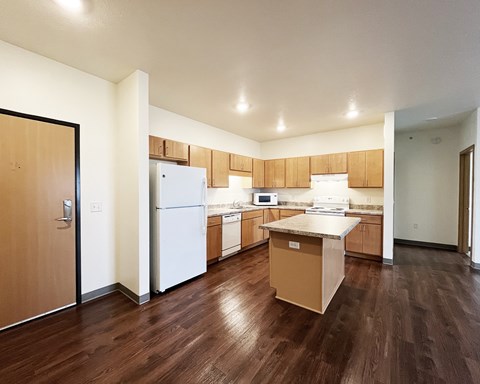 A kitchen with wooden floors and white appliances.